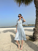 A lady wears a blue silk dress.